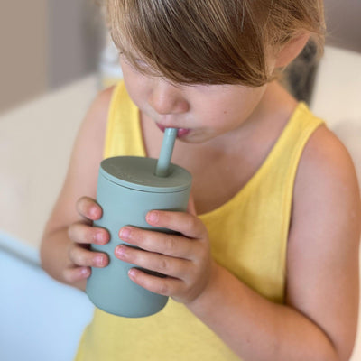 Toddler Girl drinking from a silicone cup with a straw in sage green colour