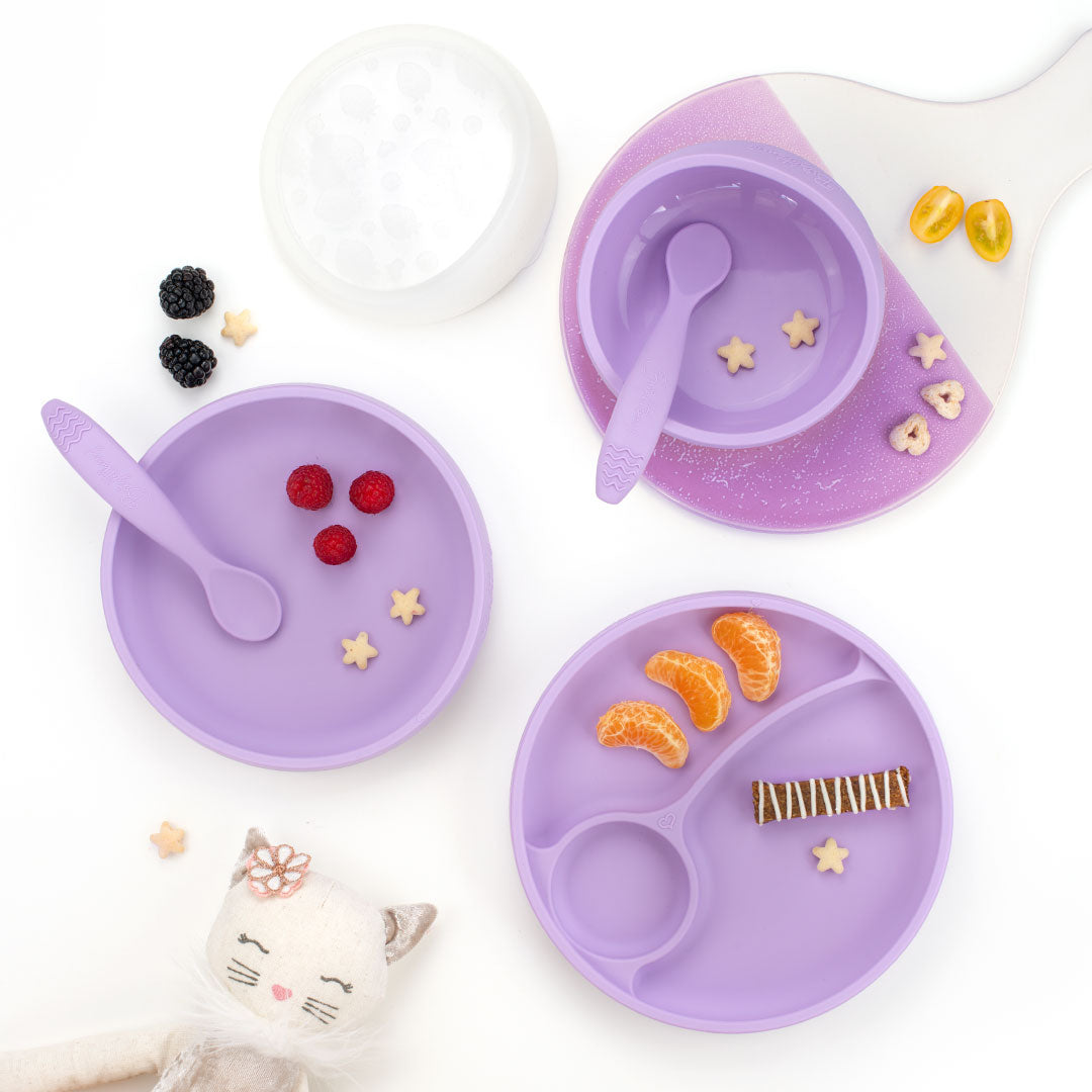 Purple children's dining set with bowl, lid, plates, and spoons on a white background