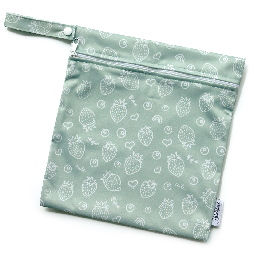 Sage green waterproof bag with white strawberry print, zip closure and snap-button carry handle.