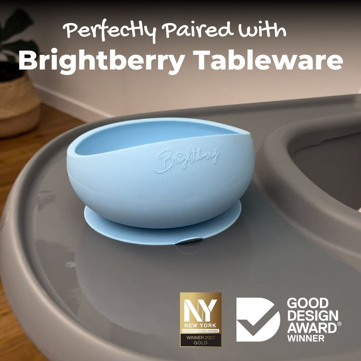 Brightberry light blue suction bowl on a grey Stokke Tripp Trapp tray with Suction Sticker installed. The text 'Perfectly Paired with Brightberry Tableware' is displayed above the bowl. The image also includes logos indicating that the product is a winner of the New York Design Award 2022 and a Good Design Award