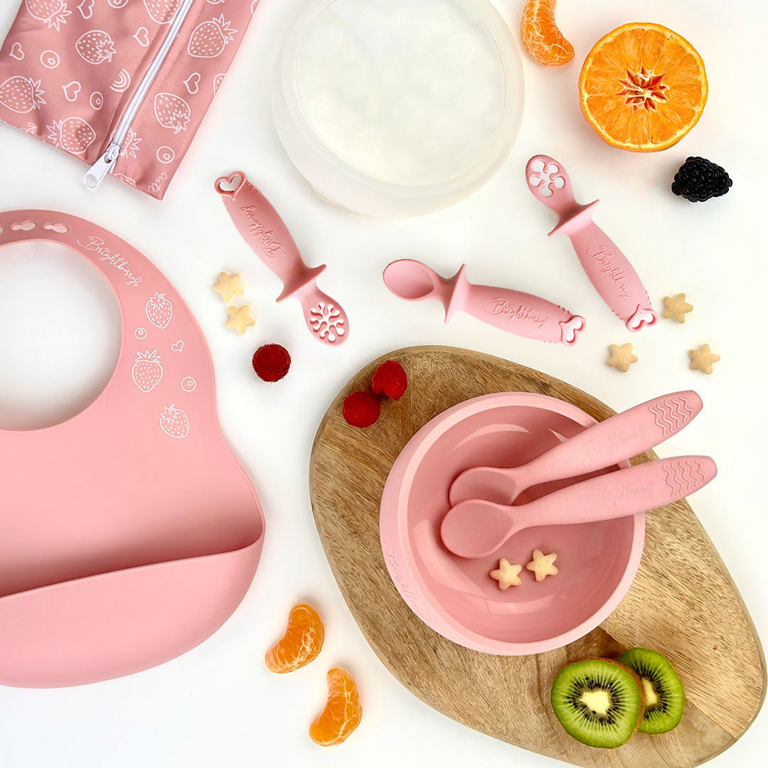 Starting Solids Set in Coral with silicone suction bowl, lid, bib, waterproof bag, two theOne spoons and theFirst baby spoons
