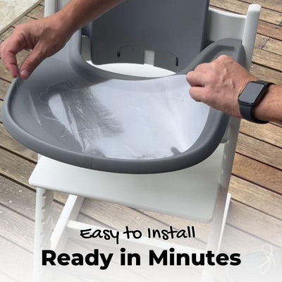 A person installing a suction sticker on a tray on a high chair. 