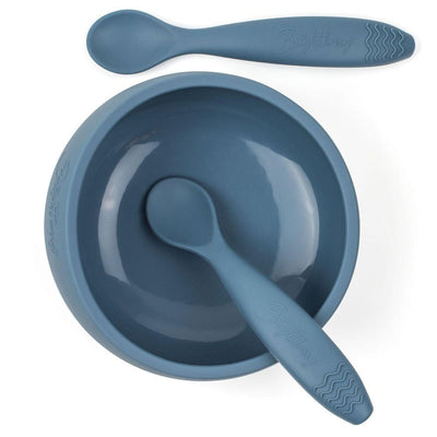 A navy blue Blueberry silicone feeding set for kids by Brightberry. The set includes a suction bowl with a strong base that keeps it in place during mealtime, and two matching silicone spoons. The spoons are soft and flexible, making them gentle on gums. The set is BPA-free and dishwasher safe, making it a safe and convenient choice for feeding kids.