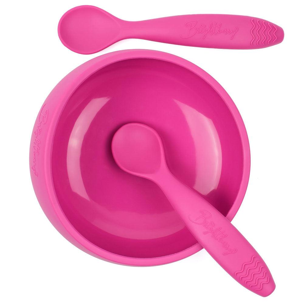 A hot pink silicone suction bowl by Brightberry for babies. The bowl has a strong suction base that keeps it in place during mealtime, even for active toddlers. The bowl is also designed with easy scooping curves to help babies feed themselves. The set also includes two matching hot pink silicone spoons with soft, flexible tips that are gentle on gums. The bowl and spoons are BPA-free and dishwasher safe.