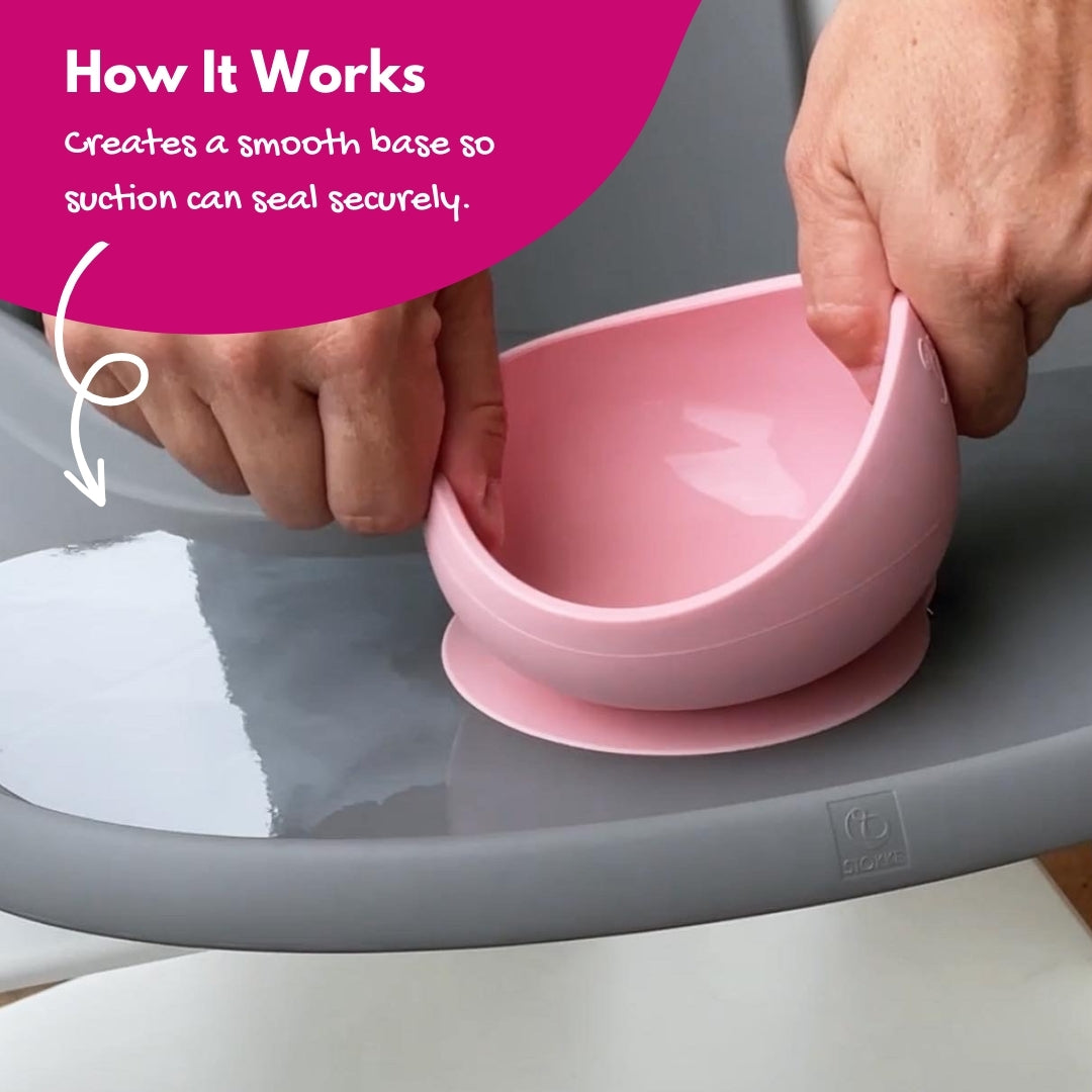 Parent pulling a silicone suction bowl off the high chair tray fitted with a clear suction sticker for secure hold.