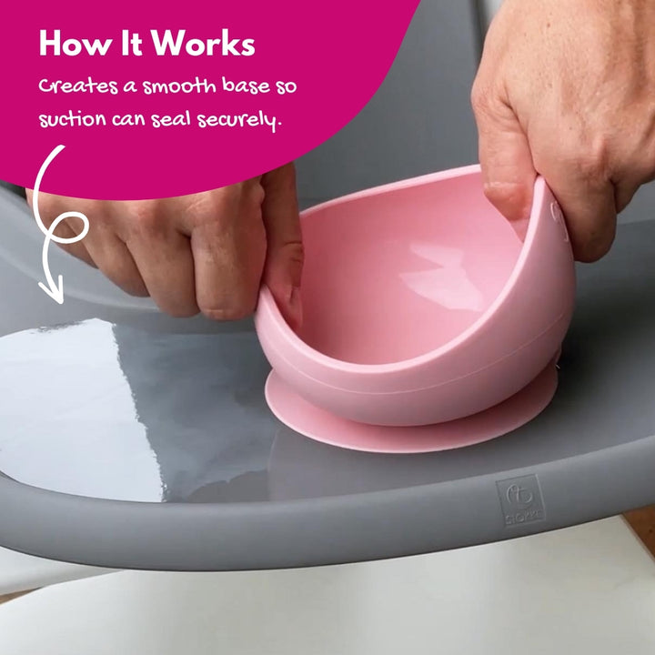Parent pulling a silicone suction bowl off the high chair tray fitted with a clear suction sticker for secure hold.