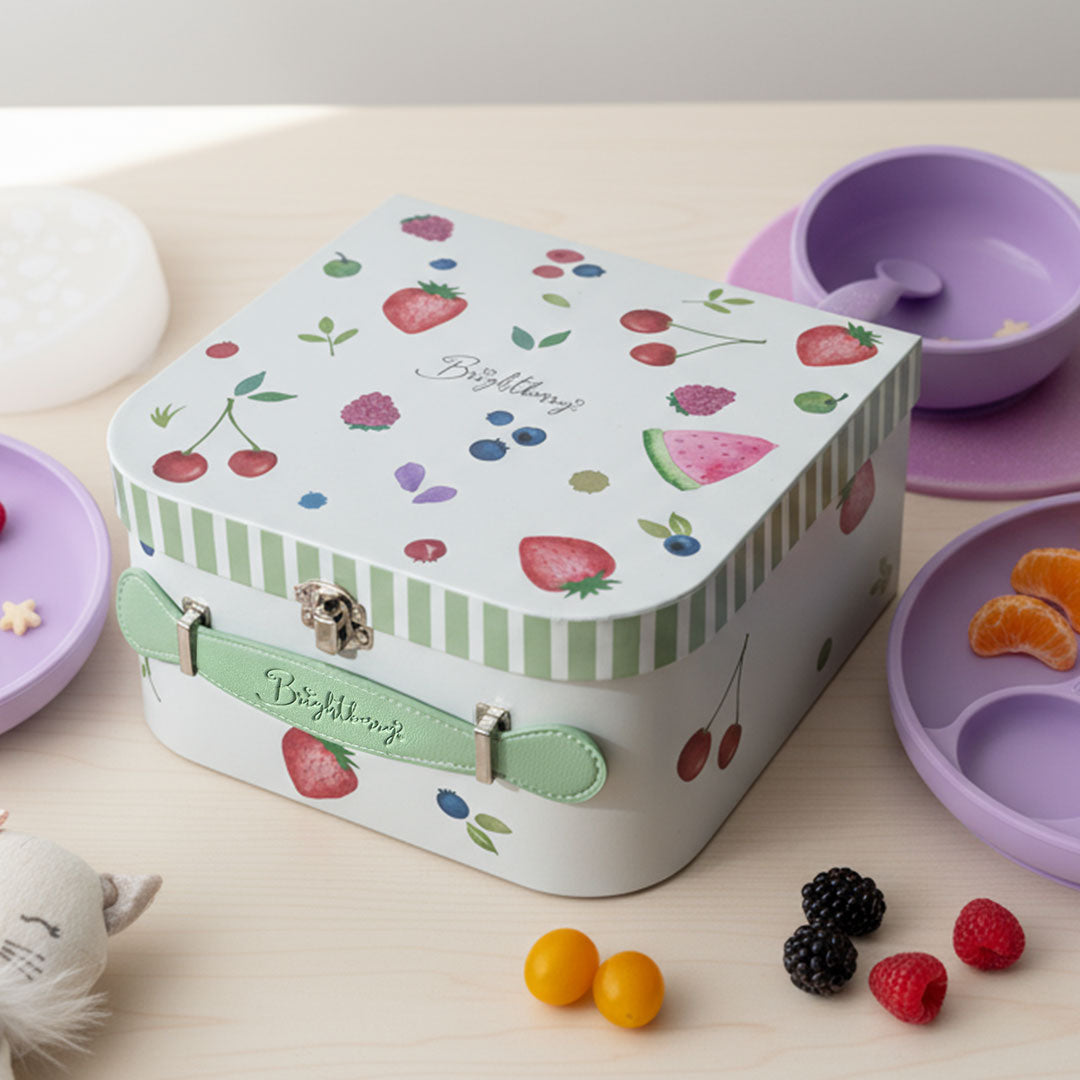 Children's feeding storage box with fruit design on a table with snacks