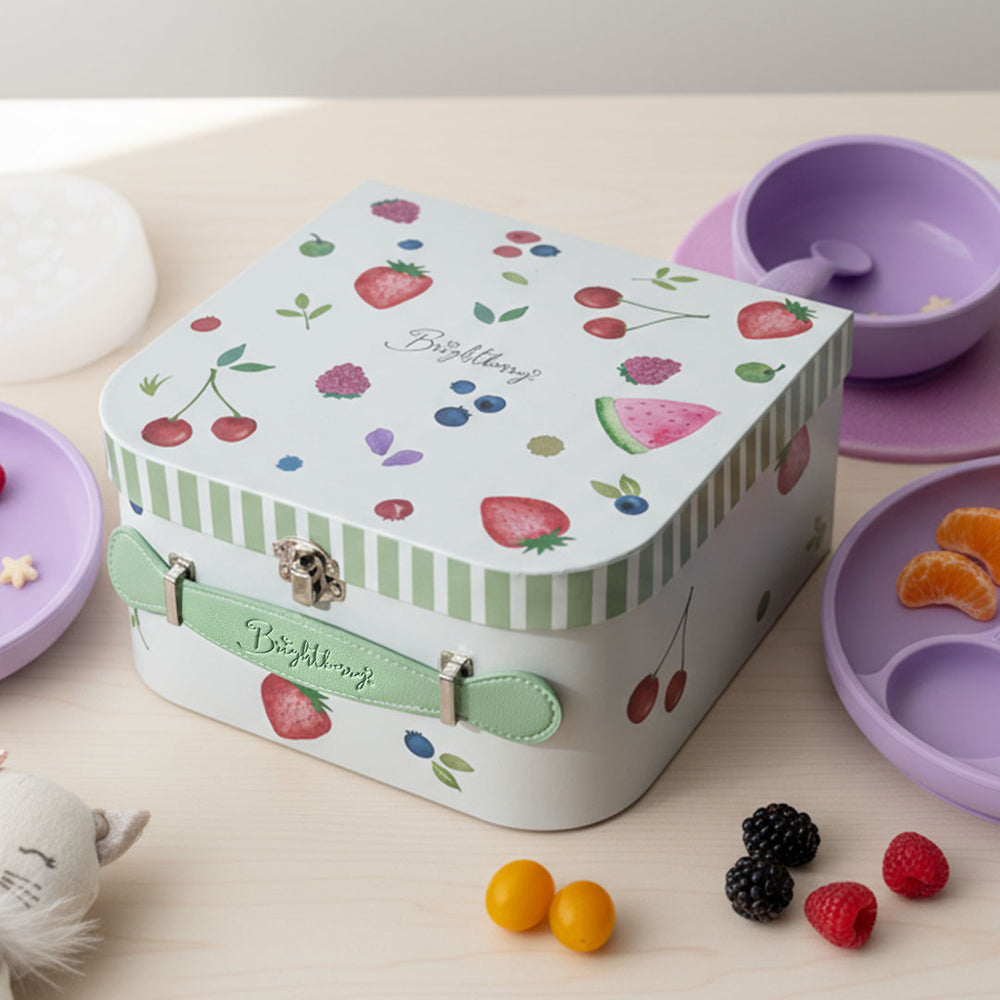 Children's feeding storage box with fruit design on a table with snacks