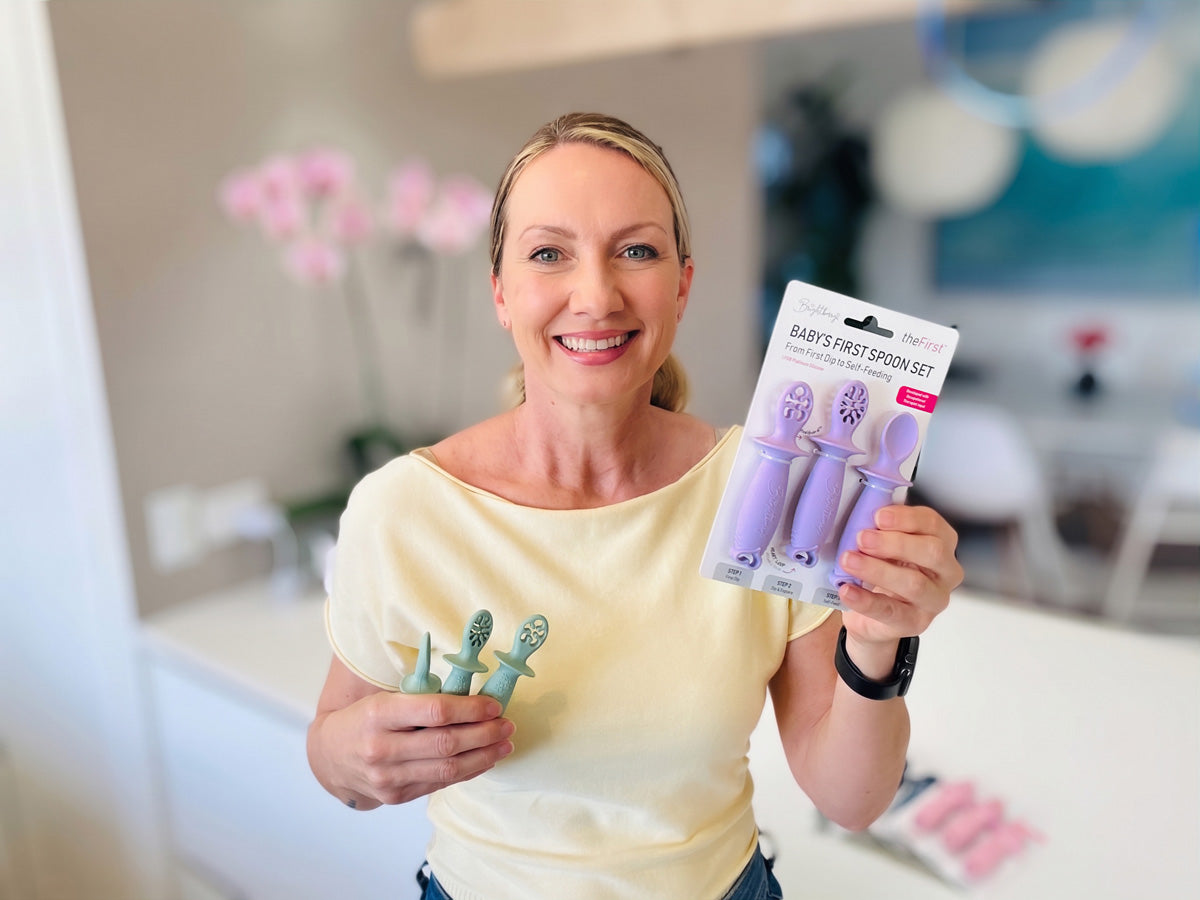 Brightberry designer Mateya Lotric holding theFirst baby spoons in Sage colour in one hand and packaged Lilac spoons set.