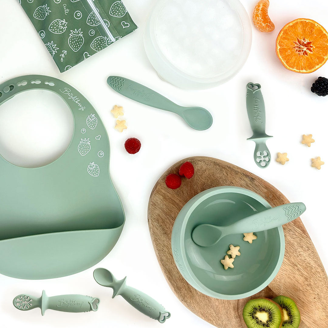 Starting Solids Set in Sage with silicone suction bowl, lid, bib, waterproof bag, two theOne spoons and theFirst baby spoons