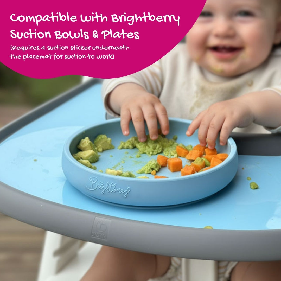 Baby is sitting in a Stokke Tripp Trapp high chair using a Brightberry suction plate and silicone placemat with food on the plate and tray.