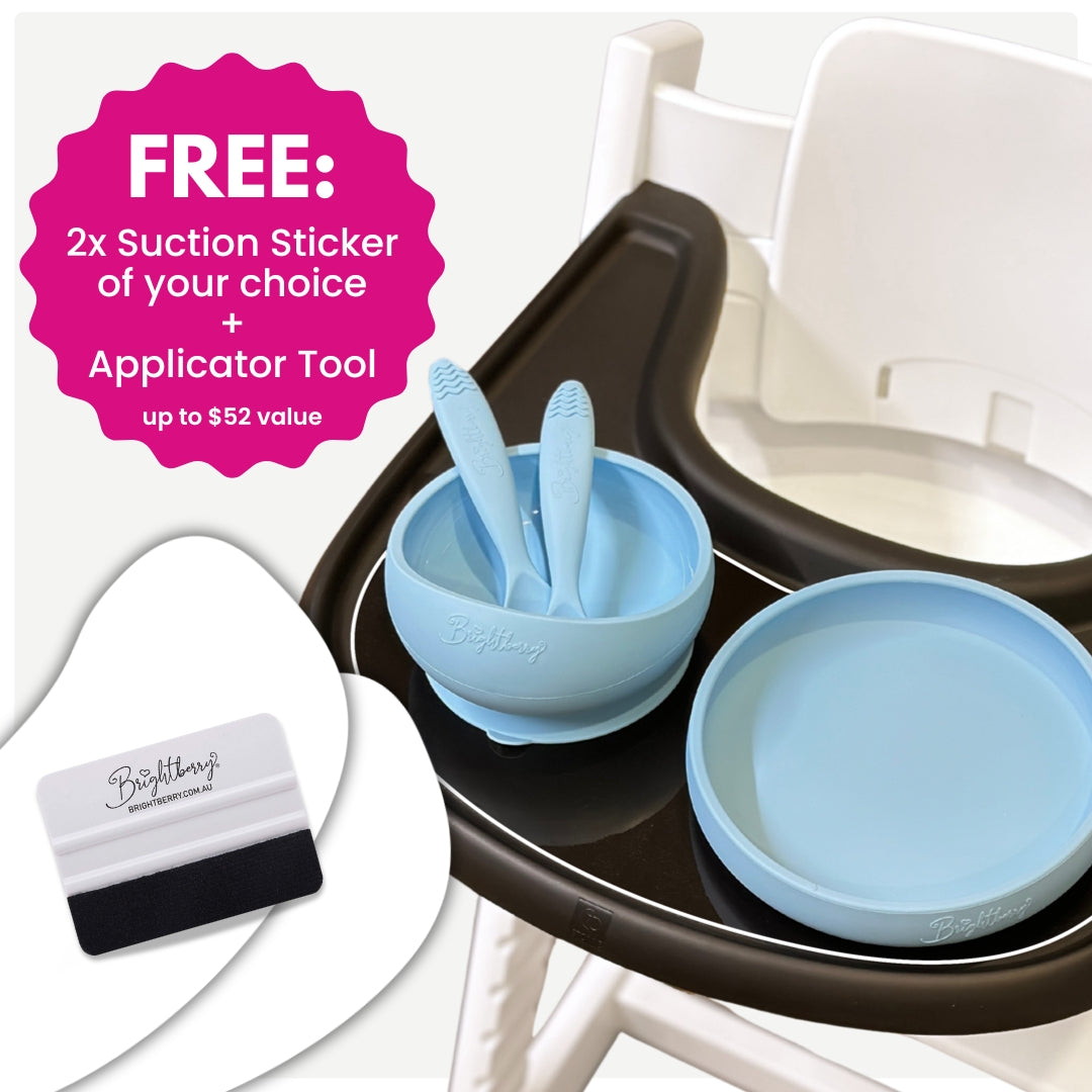 Brightberry suction bowl and plate set in light blue on a high chair tray, with two ergonomic spoons inside the bowl. Overlay text highlights a special offer: free 2x suction stickers of your choice and a free sticker applicator tool, valued at over $50.