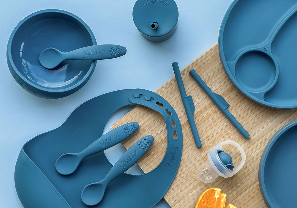 Brightberry suction bowl with teething spoons, silicone bib, divided suction plate, baby silicone fruit feeders, and stopper straws in blueberry blue colour