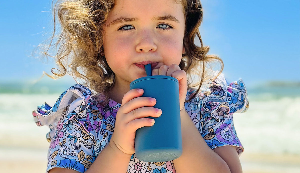 toddler girl drinking from silicone sippy smoothie cup with straw in blueberry blue colour