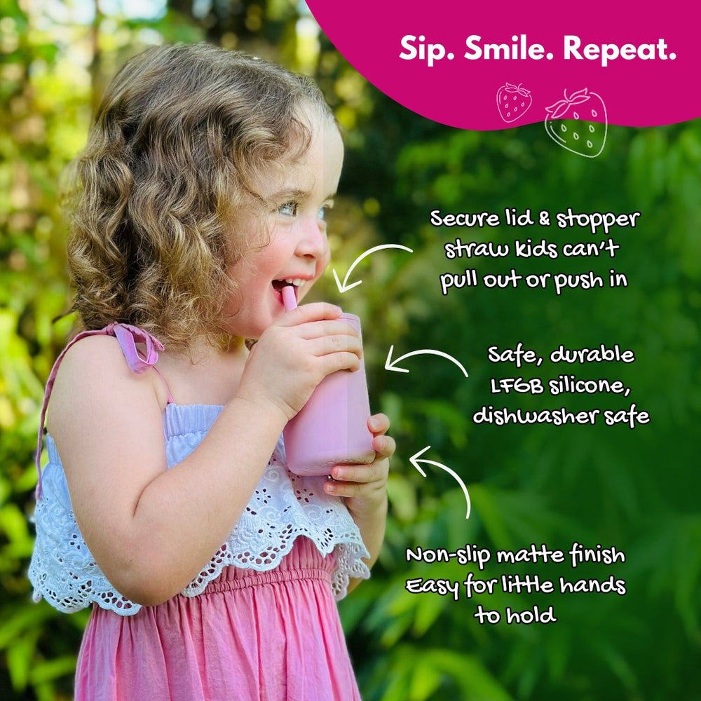 Toddler girl drinking from Brightberry lilac silicone smoothie cup outdoors — secure lid, stopper straw, non-slip grip
