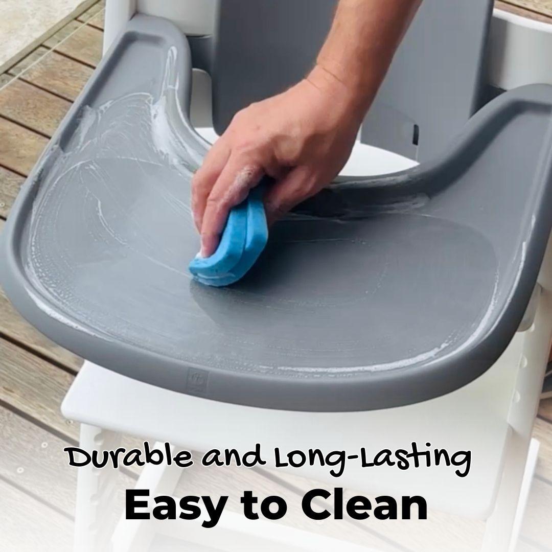 A person cleans a high chair tray with a sponge. The high chair has installed a suction sticker, which is durable, long-lasting and easy to clean.