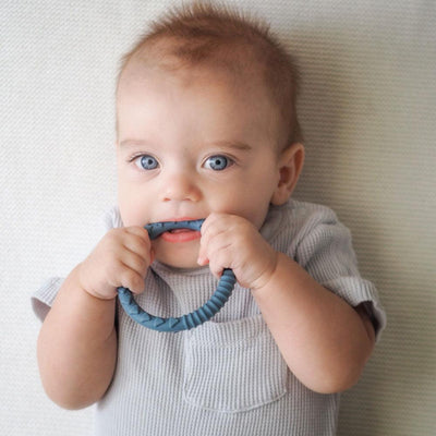 baby boy chewing teething ring in blueberry blue colour by Brightberry