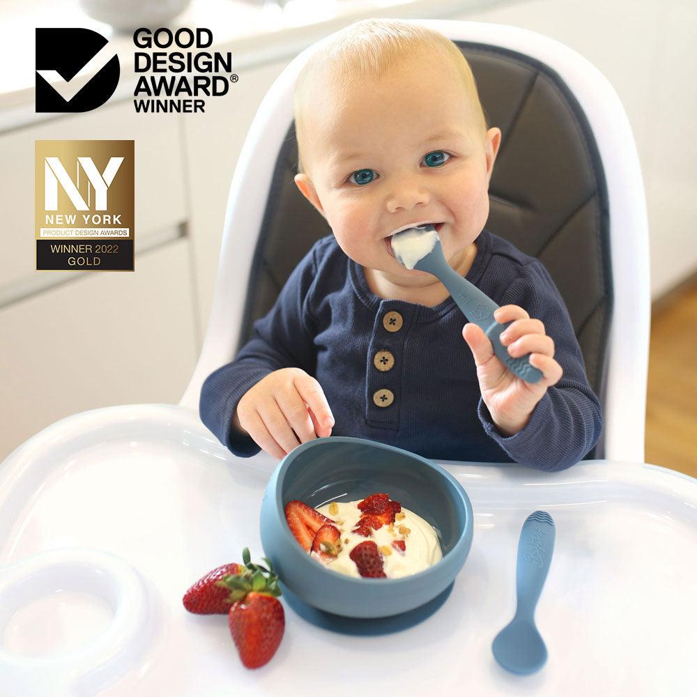 baby boy starting solid foods eating from baby bowl in blue colour sitting in a high chair. Award winning bowl and spoons by Brightberry